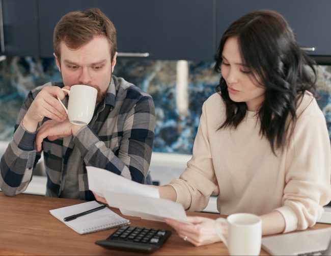 Picture of two people reading papers, one drinking coffee