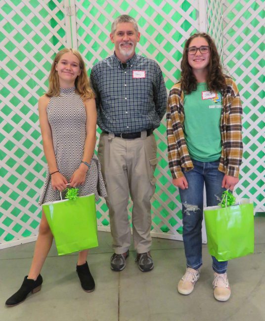 photo of two young people and one adult, in front of a green and white screen