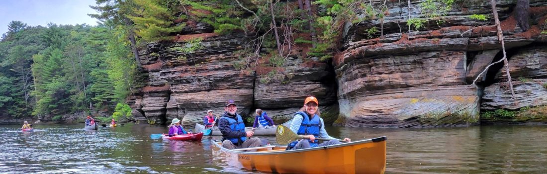 children and camp counselors in canoes paddling in the river