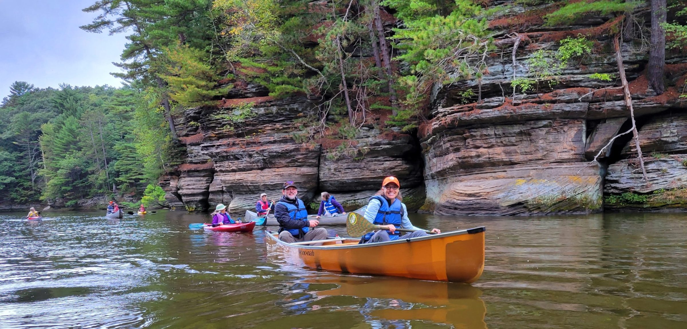children and camp counselors in canoes paddling in the river