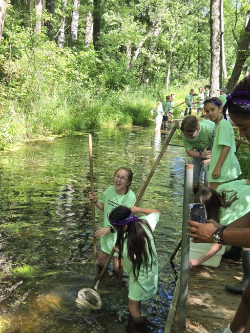 youth collecting items from a river using nets