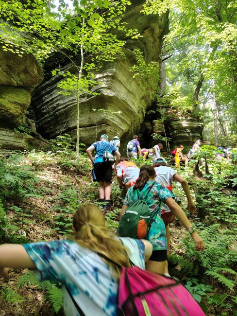 group of boys and girls hiking though a forest