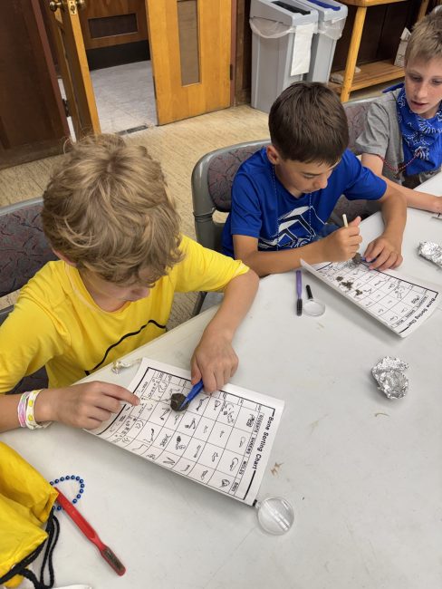 children at a table inspecting items with magnifying lens