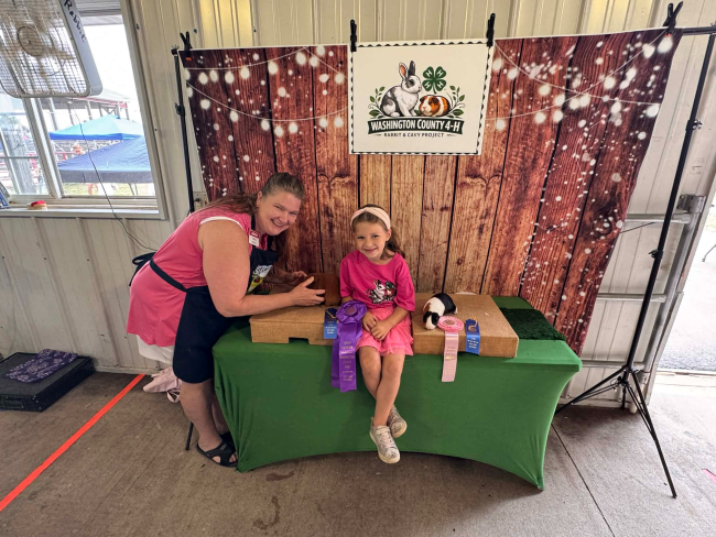 4-H member and leader posing with award ribbons at the county Fair